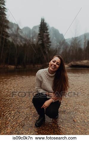 Young woman crouching in river, portrait, Yosemite Village, California, USA View Large Photo Image Picture - Young woman crouching in river, portrait, Yosemite Village, California, USA. Fotosearch