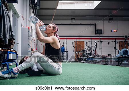 Young woman drinking water in gym View Large Photo Image Stock Image - Young woman drinking water in gym. Fotosearch