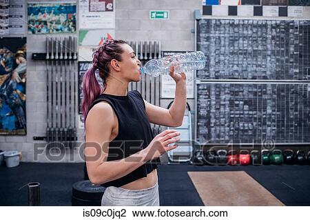 Young woman drinking water in gym View Large Photo Image Stock Image - Young woman drinking water in gym. Fotosearch