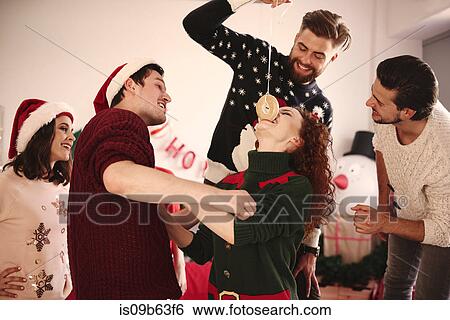 Young woman eating dangled doughnut at christmas party View Large Photo Image Stock Photograph - Young woman eating dangled doughnut at christmas party. Fotosearch