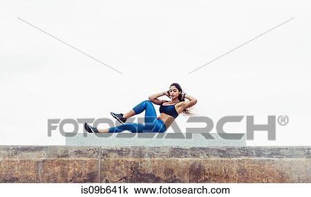 Stock Image - Young woman exercising outdoors, doing sit-ups, South Point Park, Miami Beach, Florida, USA. Fotosearch