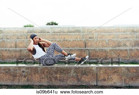 Stock Photograph - Young woman exercising outdoors, doing sit-ups on step, South Point Park, Miami Beach, Florida, USA. Fotosearch