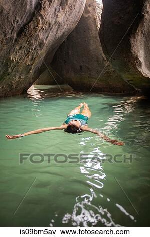 Young woman floating on water in flooded grotto, Virgin Gorda, British Virgin Islands View Large Photo Image Stock Photo - Young woman floating on water in flooded grotto, Virgin Gorda, British Virgin Islands. Fotosearch