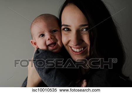 Stock Photography - Young woman holding baby son, head and shoulder portrait. Fotosearch