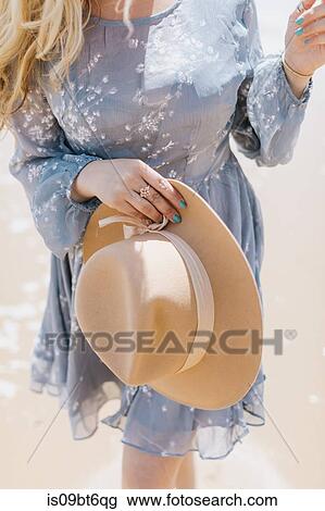 Young woman holding felt hat on beach, mid section, Menemsha, Martha's Vineyard, Massachusetts, USA View Large Photo Image Stock Image - Young woman holding felt hat on beach, mid section, Menemsha, Martha's Vineyard, Massachusetts, USA. Fotosearch