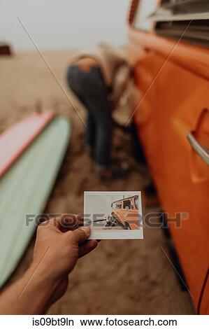 Young woman holding instant photo of boyfriend removing flat tyre on recreational vehicle at beach, Jalama, California, USA View Large Photo Image Picture - Young woman holding instant photo of boyfriend removing flat tyre on recreational vehicle at beach, Jalama, California, USA. Fotosearch