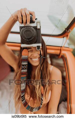 Young woman holding up instant camera in back of recreational vehicle at beach, Jalama, California, USA View Large Photo Image Stock Photography - Young woman holding up instant camera in back of recreational vehicle at beach, Jalama, California, USA. Fotosearch