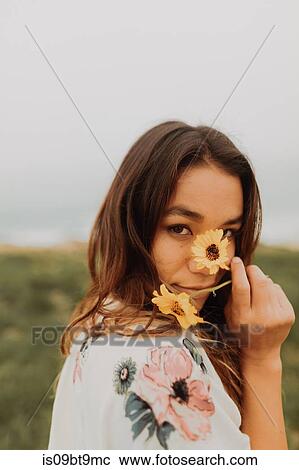 Young woman holding wildflowers in front of face at coast, portrait, Jalama, California, USA View Large Photo Image Stock Image - Young woman holding wildflowers in front of face at coast, portrait, Jalama, California, USA. Fotosearch