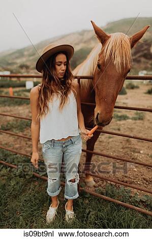 Young woman in felt hat feeding carrot to horse, Jalama, California, USA View Large Photo Image Stock Image - Young woman in felt hat feeding carrot to horse, Jalama, California, USA. Fotosearch