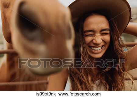 Young woman in felt hat laughing next to horse, Jalama, California, USA View Large Photo Image Stock Image - Young woman in felt hat laughing next to horse, Jalama, California, USA. Fotosearch