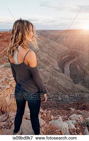 Young woman in remote setting, standing on cliff edge, looking at view, rear view, Mexican Hat, Utah, USA View Large Photo Image Stock Photo - Young woman in remote setting, standing on cliff edge, looking at view, rear view, Mexican Hat, Utah, USA. Fotosearch
