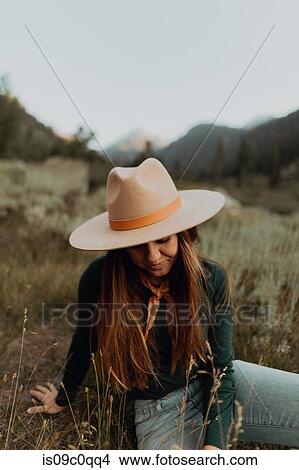 Picture - Young woman in stetson sitting and looking down in rural valley, Mineral King, California, USA. Fotosearch