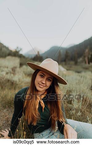 Stock Photography - Young woman in stetson sitting in rural valley, portrait, Mineral King, California, USA. Fotosearch