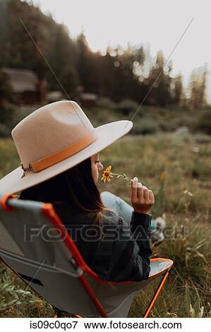 Young woman in stetson smelling wildflower on deck chair in rural valley, rear view, Mineral King, California, USA View Large Photo Image Stock Photo - Young woman in stetson smelling wildflower on deck chair in rural valley, rear view, Mineral King, California, USA. Fotosearch