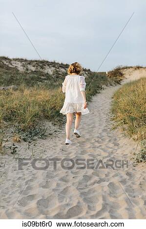 Young woman in white dress walking on coastal dunes, rear view, Menemsha, Martha's Vineyard, Massachusetts, USA View Large Photo Image Stock Image - Young woman in white dress walking on coastal dunes, rear view, Menemsha, Martha's Vineyard, Massachusetts, USA. Fotosearch