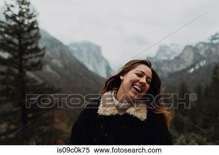 Stock Photography - Young woman laughing in mountain landscape, head and shoulders, Yosemite Village, California, USA. Fotosearch