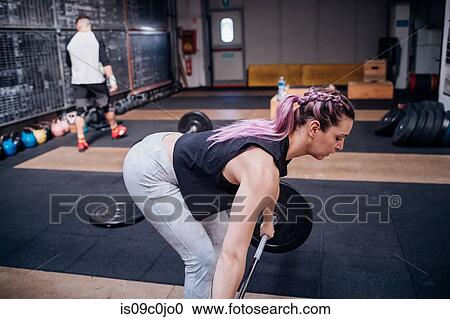 Young woman lifting barbell in gym View Large Photo Image Stock Image - Young woman lifting barbell in gym. Fotosearch