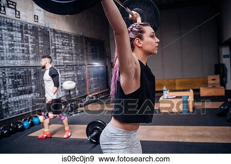 Young woman lifting barbell in gym View Large Photo Image Stock Photo - Young woman lifting barbell in gym. Fotosearch