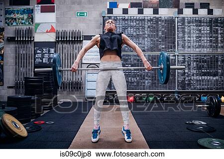 Young woman lifting barbell in gym View Large Photo Image Stock Photo - Young woman lifting barbell in gym. Fotosearch