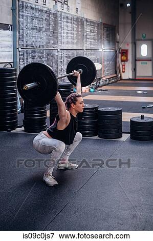 Young woman lifting barbell in gym View Large Photo Image Stock Photo - Young woman lifting barbell in gym. Fotosearch