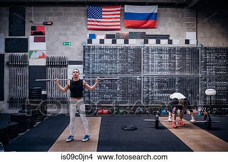 Young woman lifting weight bar in gym View Large Photo Image Picture - Young woman lifting weight bar in gym. Fotosearch
