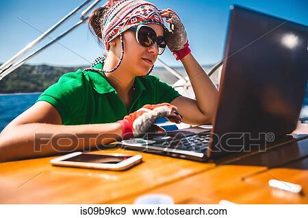 Young woman looking at laptop aboard yacht near coast, Croatia View Large Photo Image Stock Photo - Young woman looking at laptop aboard yacht near coast, Croatia. Fotosearch