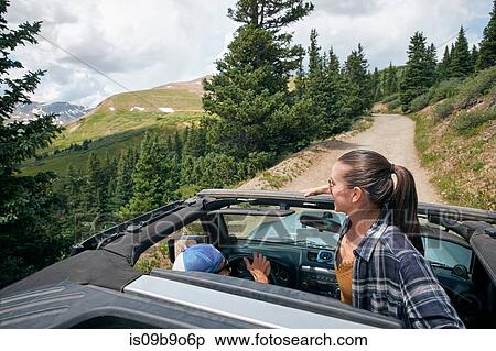 Stock Photography - Young woman looking out from four wheel convertible in Rocky mountains, Breckenridge, Colorado, USA. Fotosearch