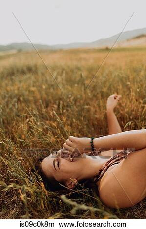Young woman lying in field of long grass laughing, Exeter, California, USA View Large Photo Image Picture - Young woman lying in field of long grass laughing, Exeter, California, USA. Fotosearch
