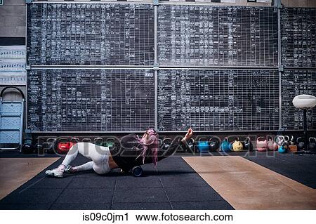 Young woman massaging body with foam roller in gym View Large Photo Image Stock Image - Young woman massaging body with foam roller in gym. Fotosearch
