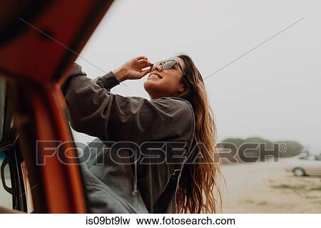 Stock Photo - Young woman next to recreational vehicle at beach, Jalama, California, USA. Fotosearch