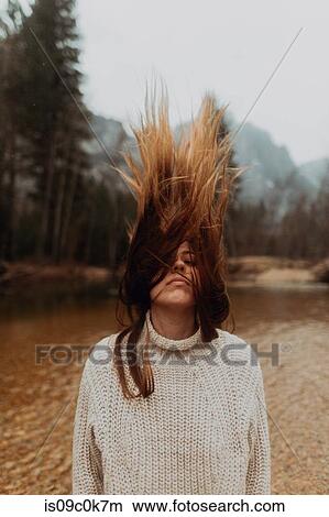 Picture - Young woman on riverbank shaking long brown hair, Yosemite Village, California, USA. Fotosearch