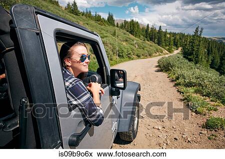 Stock Photo - Young woman on road trip looking from car window in Rocky mountains, Breckenridge, Colorado, USA. Fotosearch