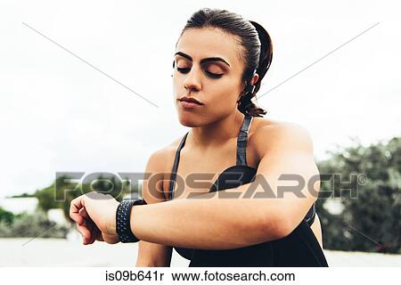 Stock Photography - Young woman outdoors, checking activity tracker, South Point Park, Miami Beach, Florida, USA. Fotosearch