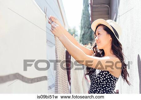 Young woman outdoors, hanging washing on washing line View Large Photo Image Stock Photo - Young woman outdoors, hanging washing on washing line. Fotosearch