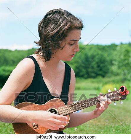 Young woman, outdoors, playing ukulele View Large Photo Image Stock Image - Young woman, outdoors, playing ukulele. Fotosearch