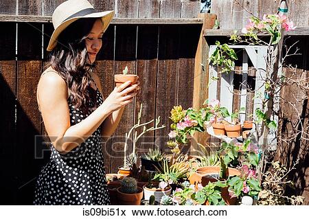 Young woman outdoors, tending to potted plants in garden View Large Photo Image Stock Photo - Young woman outdoors, tending to potted plants in garden. Fotosearch
