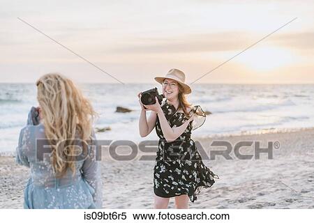 Young woman photographing friend on windy beach, Menemsha, Martha's Vineyard, Massachusetts, USA View Large Photo Image Stock Photography - Young woman photographing friend on windy beach, Menemsha, Martha's Vineyard, Massachusetts, USA. Fotosearch