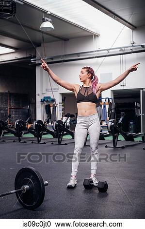Young woman pointing fingers upwards in gym View Large Photo Image Stock Image - Young woman pointing fingers upwards in gym. Fotosearch