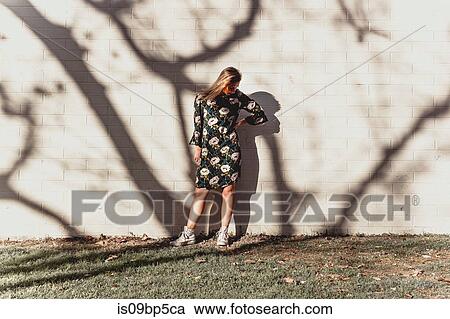 Young woman posing against wall with shadow of trees View Large Photo Image Stock Image - Young woman posing against wall with shadow of trees. Fotosearch
