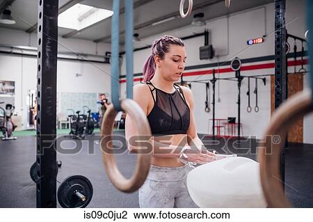 Stock Image - Young woman powdering palms in gym. Fotosearch