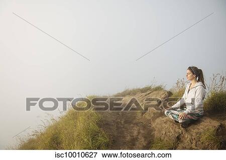 Young woman practicing yoga on top of misty mountain, Bali, Indonesia View Large Photo Image Stock Photo - Young woman practicing yoga on top of misty mountain, Bali, Indonesia. Fotosearch