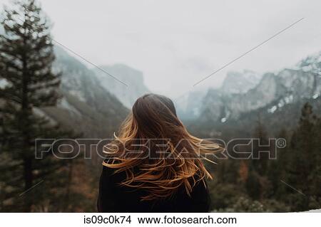 Young woman shaking long brown hair in mountain landscape, rear view, Yosemite Village, California, USA View Large Photo Image Picture - Young woman shaking long brown hair in mountain landscape, rear view, Yosemite Village, California, USA. Fotosearch