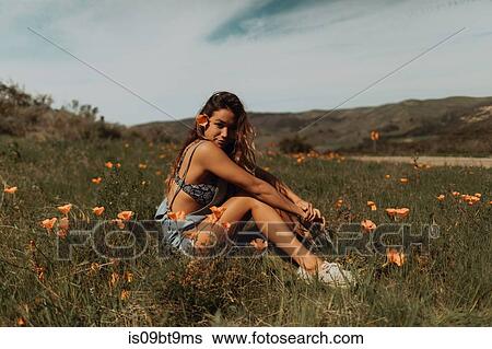 Stock Photograph - Young woman sitting in field of wildflowers, portrait, Jalama, California, USA. Fotosearch