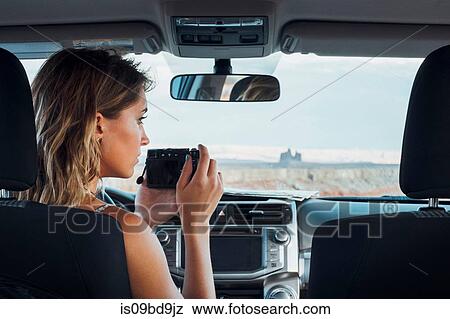 Young woman sitting in vehicle, taking photo through windscreen, using camera, Mexican Hat, Utah, USA View Large Photo Image Stock Photo - Young woman sitting in vehicle, taking photo through windscreen, using camera, Mexican Hat, Utah, USA. Fotosearch