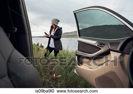 Young woman standing beside Dillon Reservoir, holding smartphone, view through parked car, Silverthorne, Colorado, USA View Large Photo Image Stock Image - Young woman standing beside Dillon Reservoir, holding smartphone, view through parked car, Silverthorne, Colorado, USA. Fotosearch