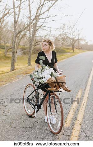 Young woman standing by bicycle with bunch of flowers on rural road, Menemsha, Martha's Vineyard, Massachusetts, USA View Large Photo Image Stock Photograph - Young woman standing by bicycle with bunch of flowers on rural road, Menemsha, Martha's Vineyard, Massachusetts, USA. Fotosearch
