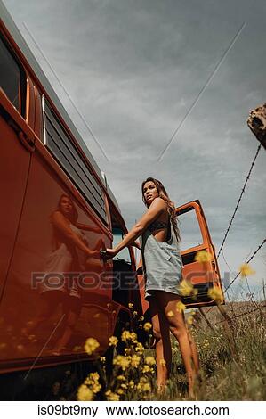 Stock Photo - Young woman standing by recreational vehicle on rural roadside, Jalama, California, USA. Fotosearch