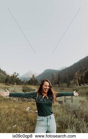Stock Photo - Young woman standing with open arms in rural valley, Mineral King, California, USA. Fotosearch