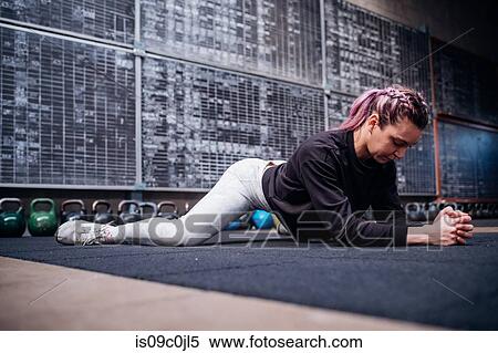 Young woman stretching in gym View Large Photo Image Stock Photography - Young woman stretching in gym. Fotosearch