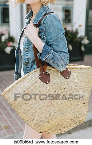 Young woman strolling along street carrying straw bag, mid section, Menemsha, Martha's Vineyard, Massachusetts, USA View Large Photo Image Stock Image - Young woman strolling along street carrying straw bag, mid section, Menemsha, Martha's Vineyard, Massachusetts, USA. Fotosearch